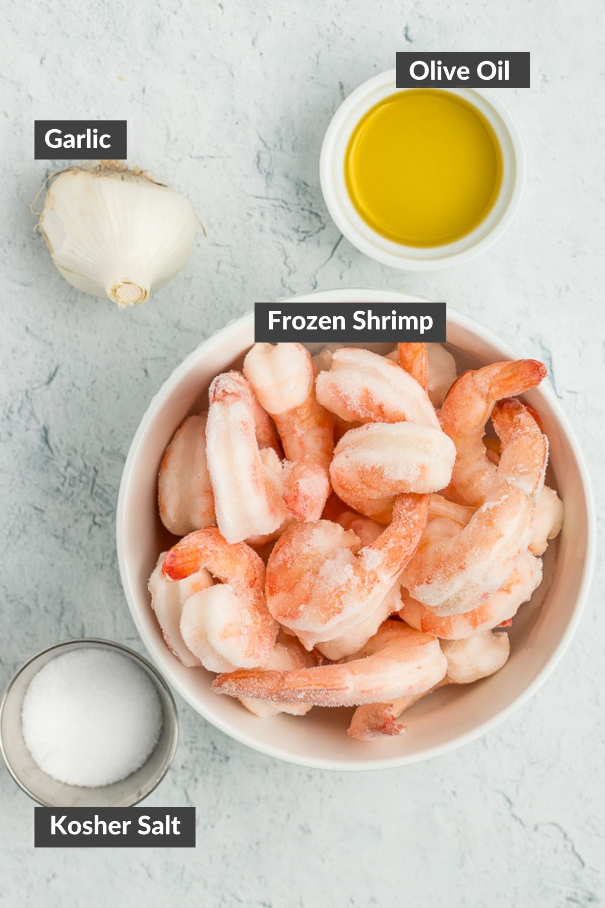 a bowl of olive oil, salt, shrimp, and a head of garlic.
