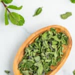 a small wooden bowl full of dried mint.