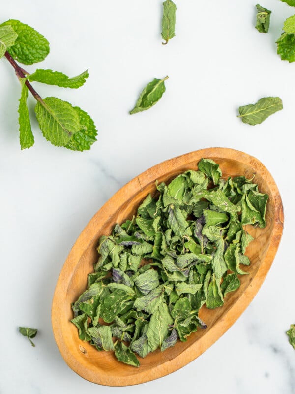 a small wooden bowl full of dried mint.