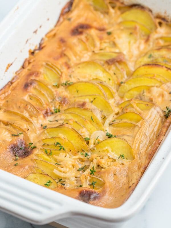 a white baking dish of gluten-free scalloped potatoes topped with thyme