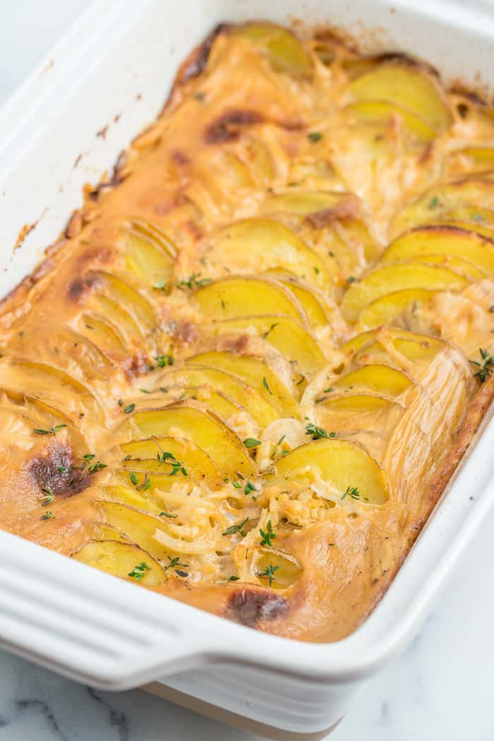 a white baking dish of gluten-free scalloped potatoes topped with thyme