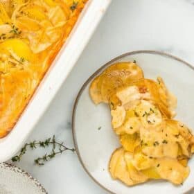 a grey dish with a scoop of potato casserole with fresh thyme
