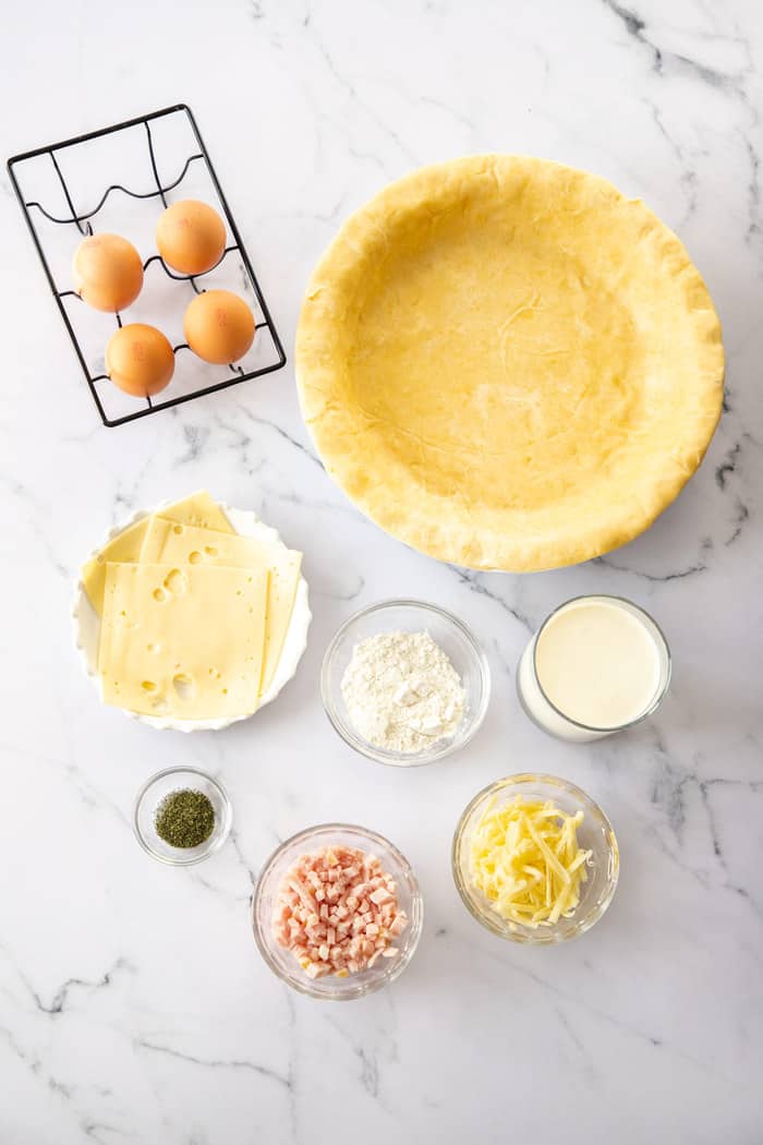 a pie crust, eggs, and bowls of other ingredients on a white board