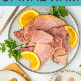 a plate of ham with oranges and parsley.