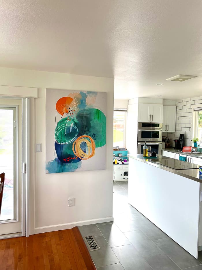 a colorful modern art canvas on a wall in a kitchen