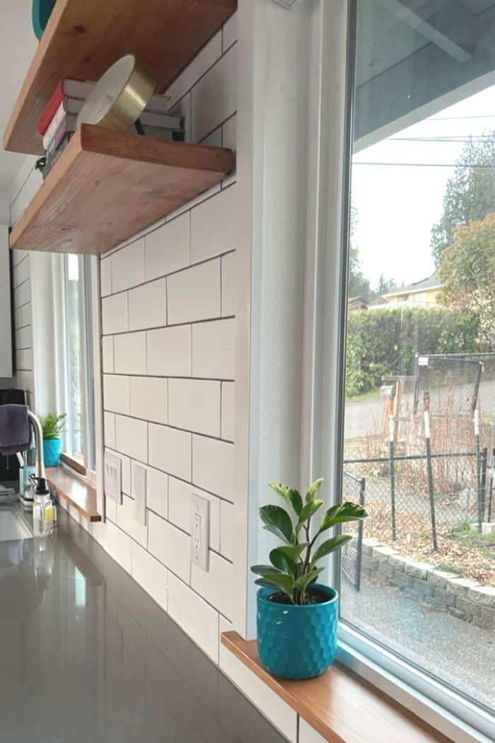 a teal flowerpot on a windowsill in a kitchen.