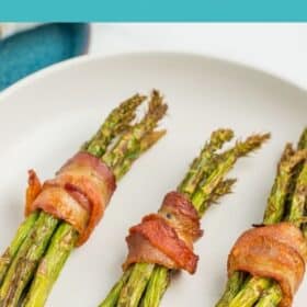 3 bundles of air fryer asparagus wrapped in bacon in a white bowl.