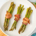 a white dish with asparagus bundles.