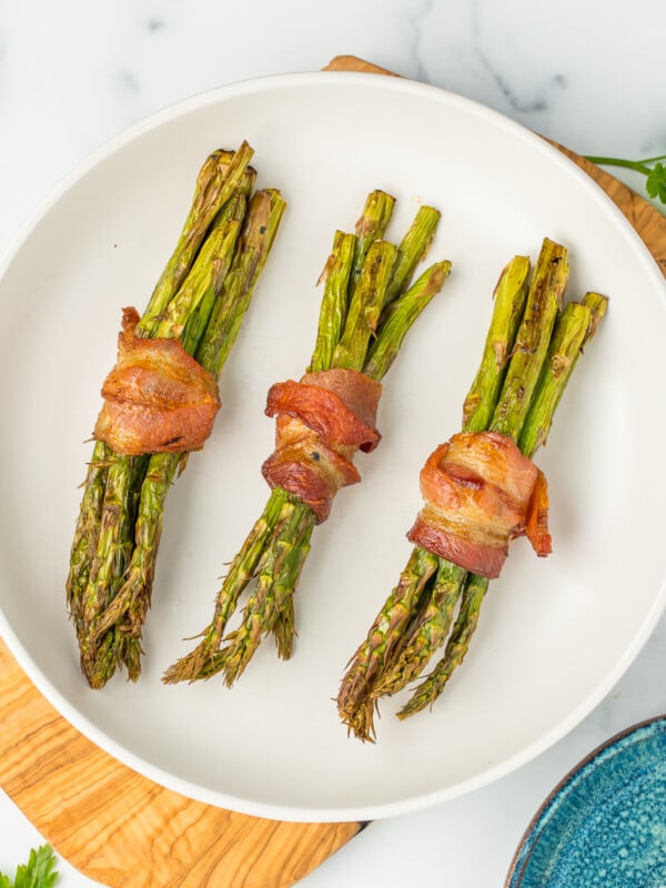 a white dish with asparagus bundles.