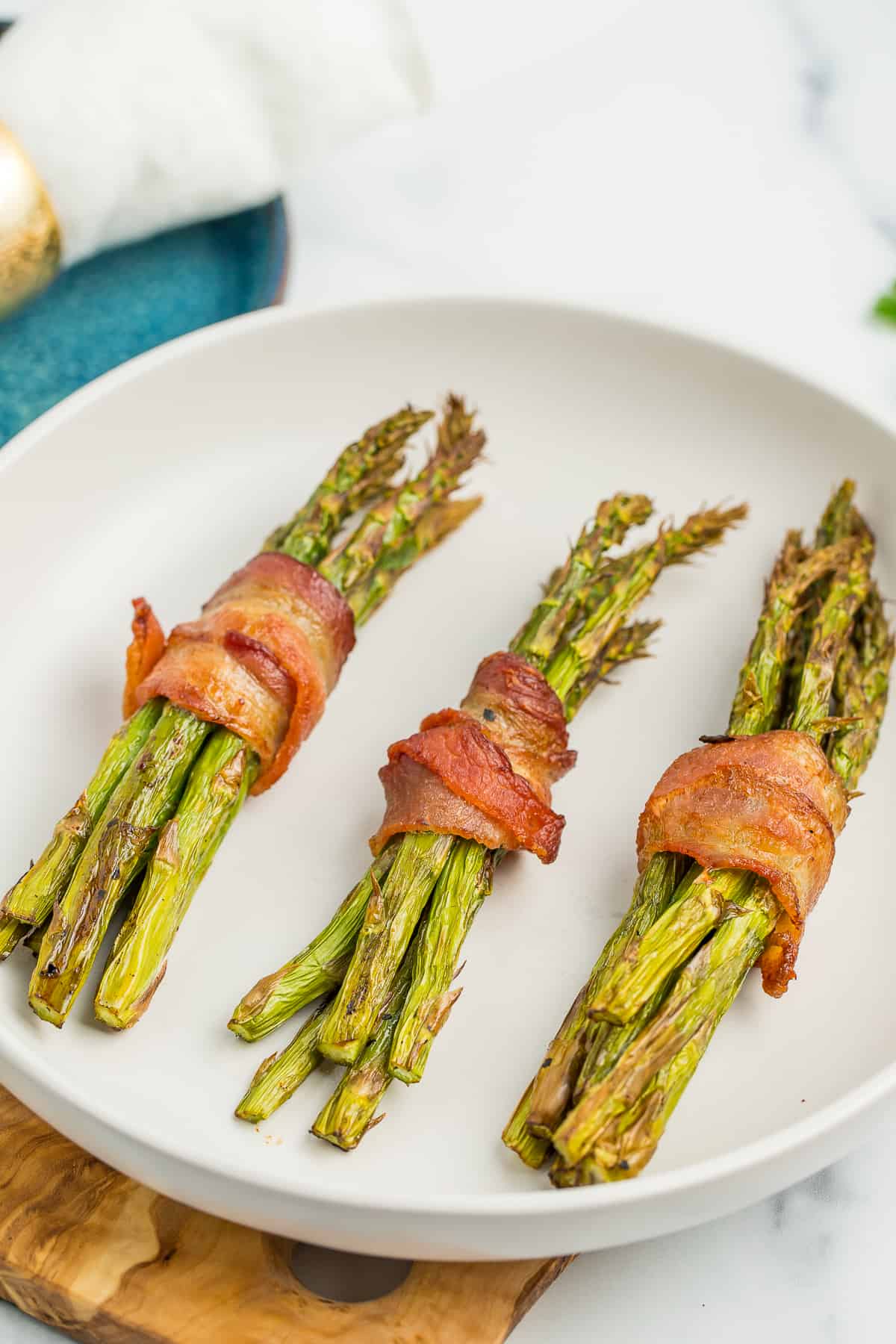 3 bundles of air fryer asparagus wrapped in bacon in a white bowl.