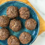 a blue dish with 8 banana protein balls on a wooden platter.