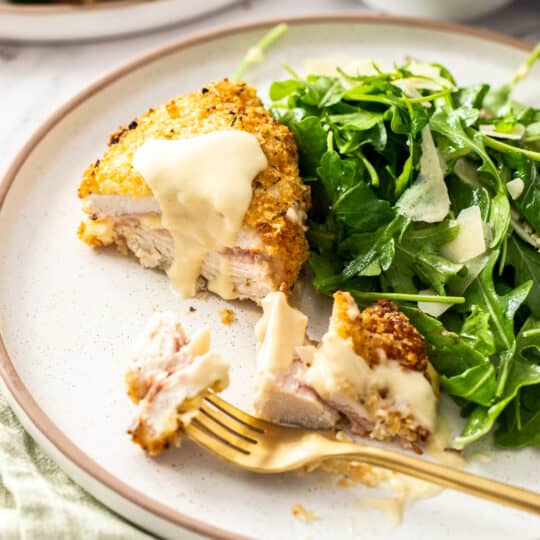 a crispy chicken cutlet with Parmesan sauce on a plate.