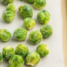 a tray with parchment covered in frozen brussel sprouts.