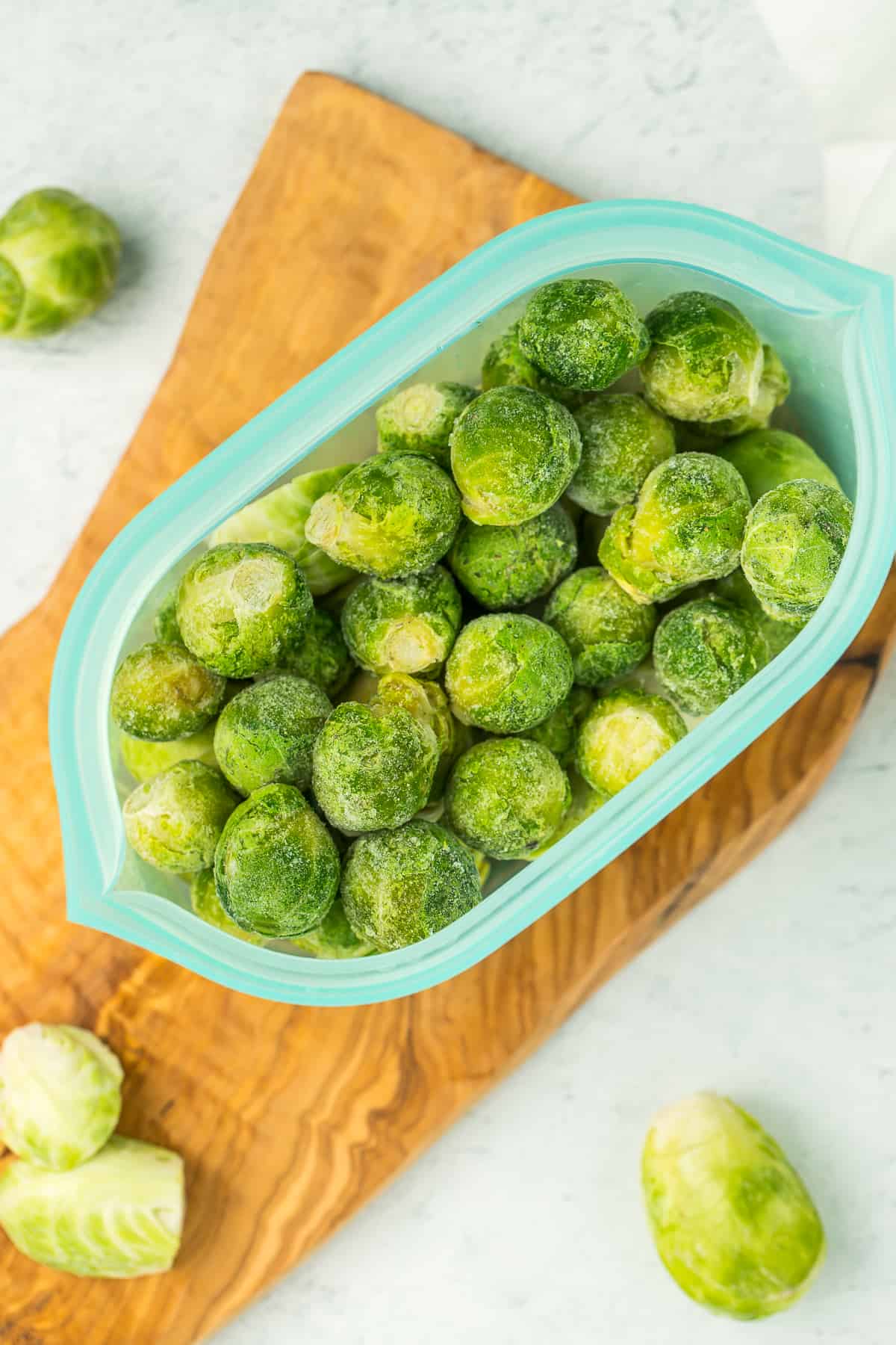 a blue reusable silicone bag full of frozen brussel sprouts.