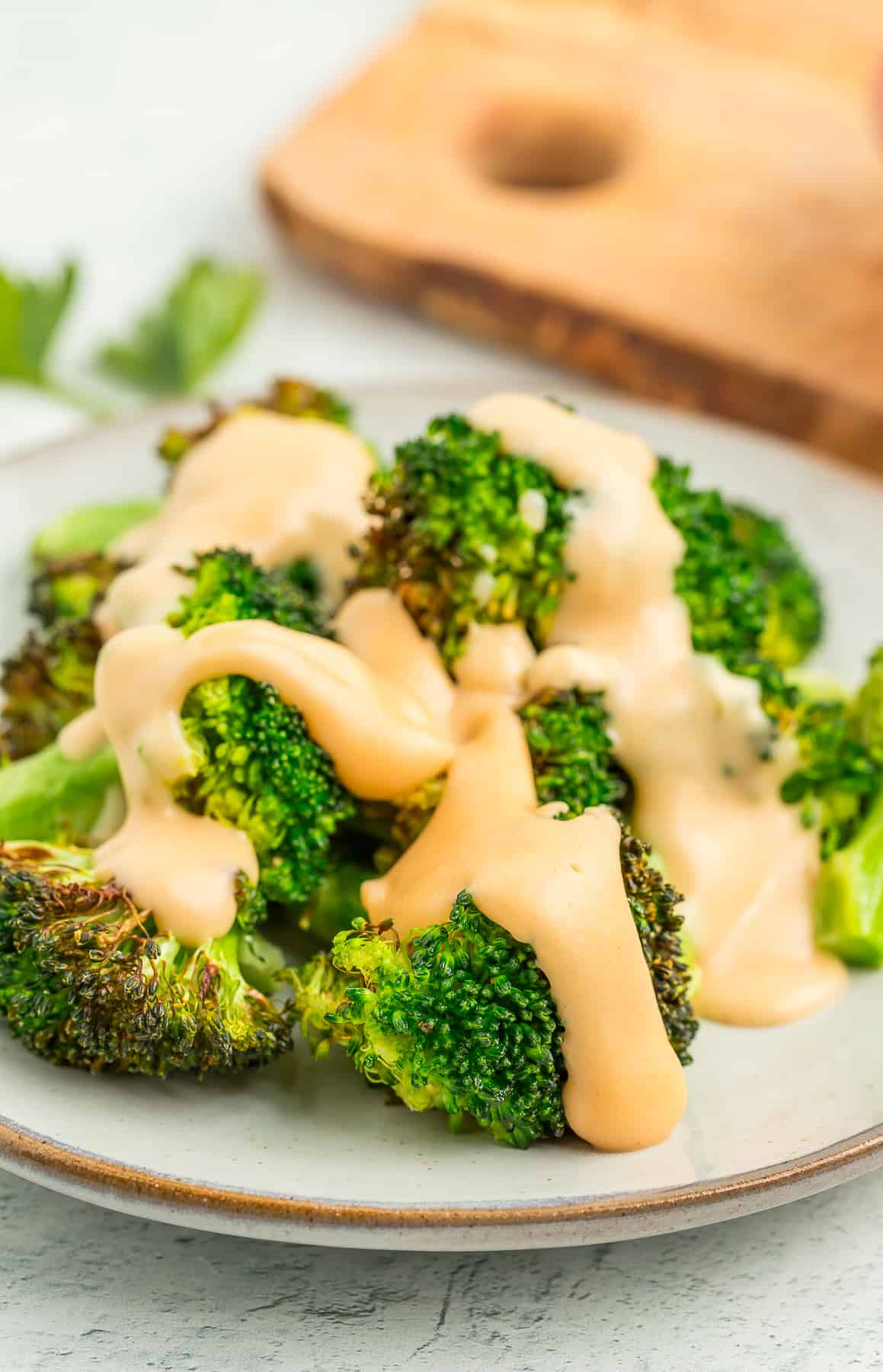a grey plate with roasted broccoli drizzled in gluten-free cheese sauce