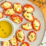 cheese stuffed tomatoes and olive oil on a grey plate.