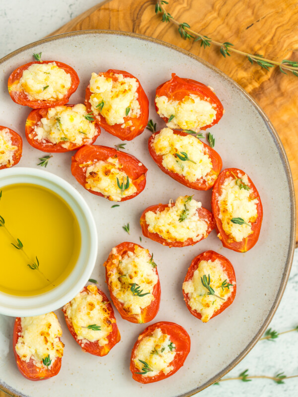 cheese stuffed tomatoes and olive oil on a grey plate.