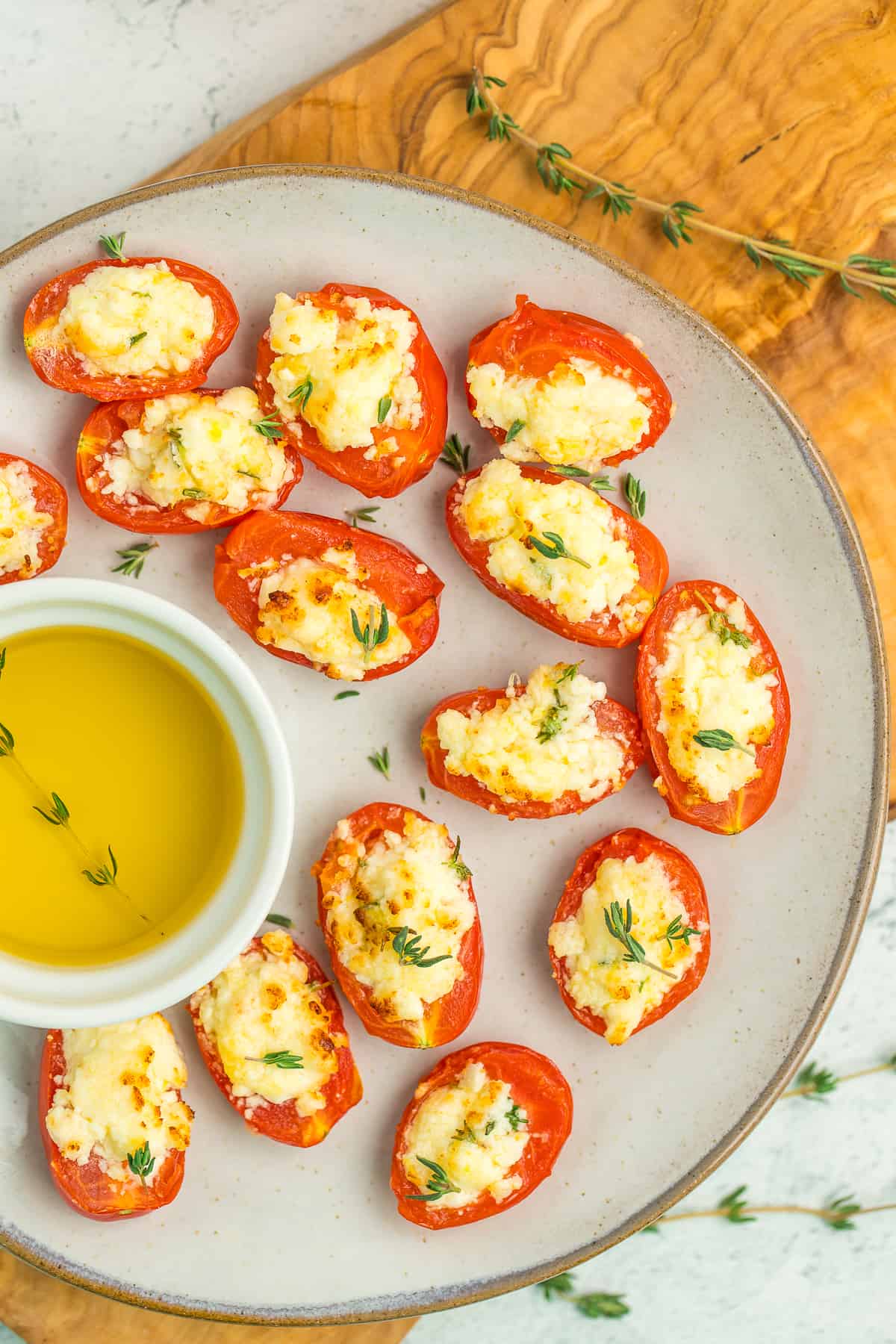 cheese stuffed tomatoes and olive oil on a grey plate.