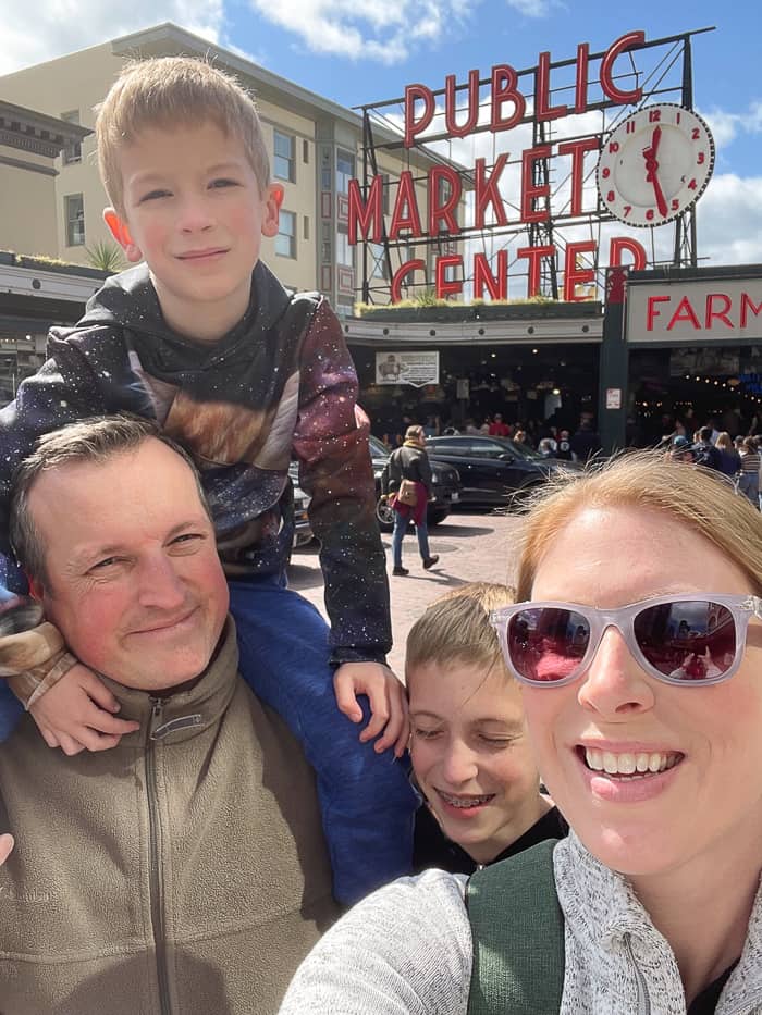 a family in front of the pike's place market sign