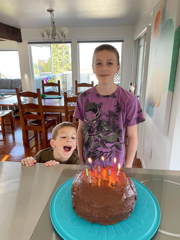 2 boys in front of a birthday cake.