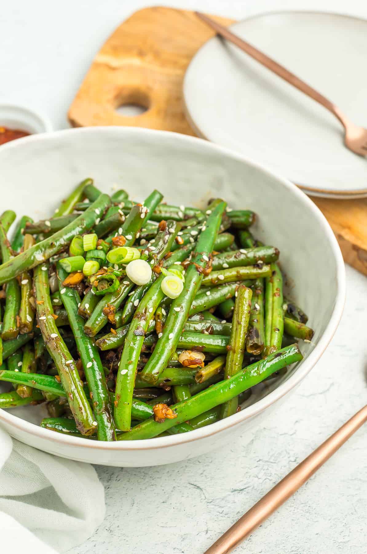 green beans in a white bowl with a gold fork