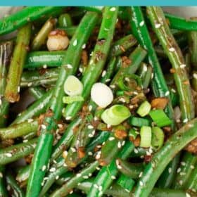 a white bowl with stir fried green beans and sliced green onions.