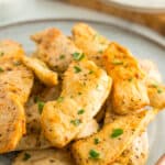 a plate of air fryer chicken tenders without breading topped with parsley.