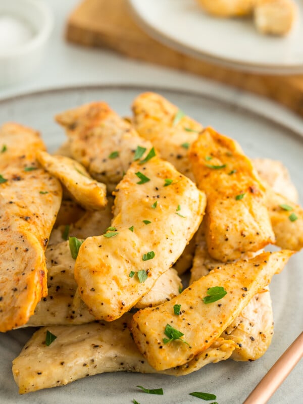 a plate of air fryer chicken tenders without breading topped with parsley.