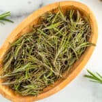 a wooden bowl full of dried rosemary.