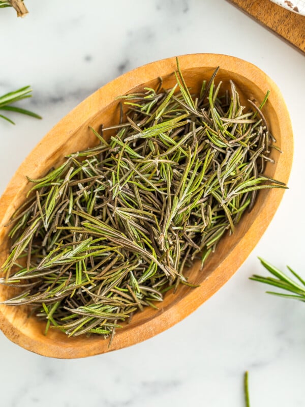 a wooden bowl full of dried rosemary.