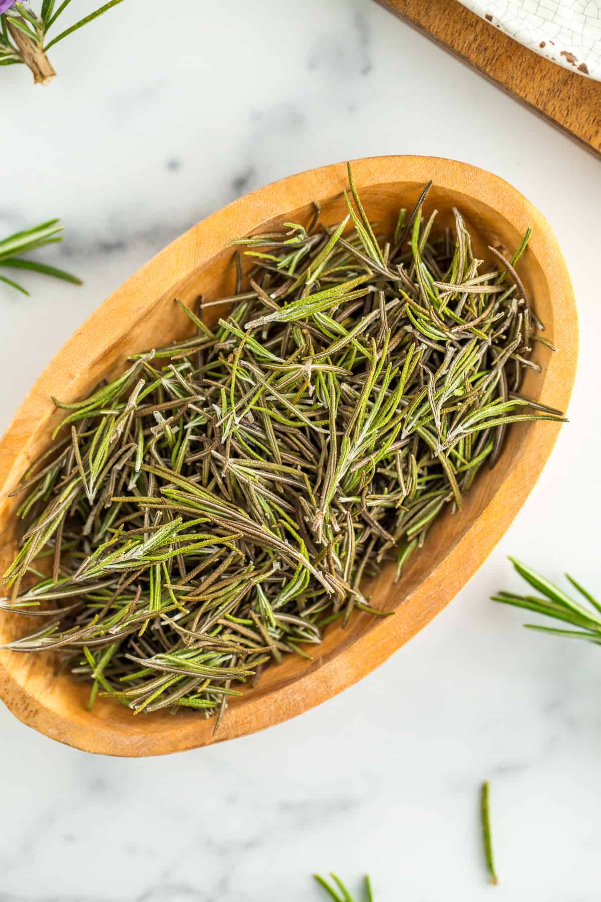 a wooden bowl full of dried rosemary.