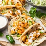 a plate of air fryer shrimp tacos with jalapenos and cilantro.