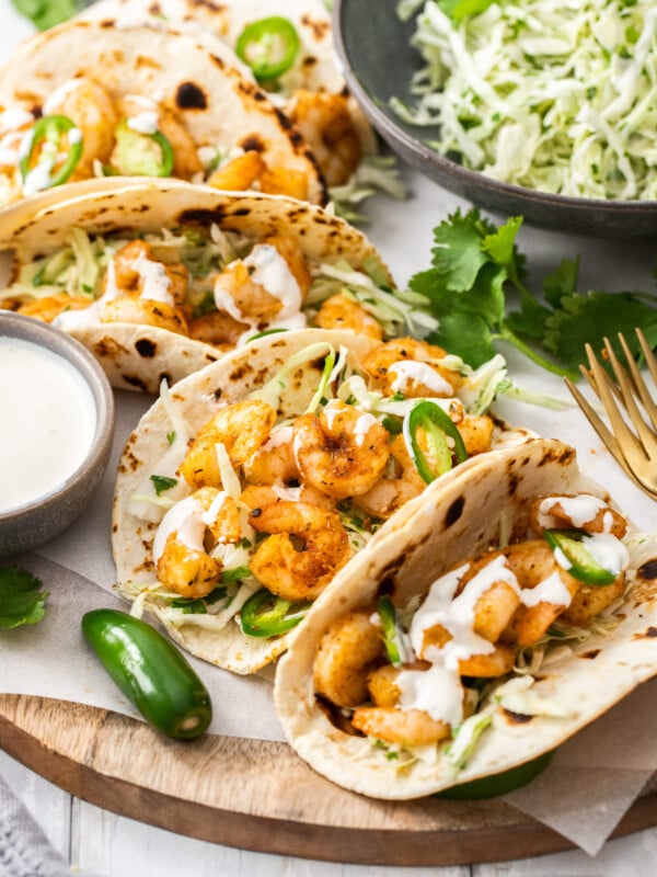 a plate of air fryer shrimp tacos with jalapenos and cilantro.