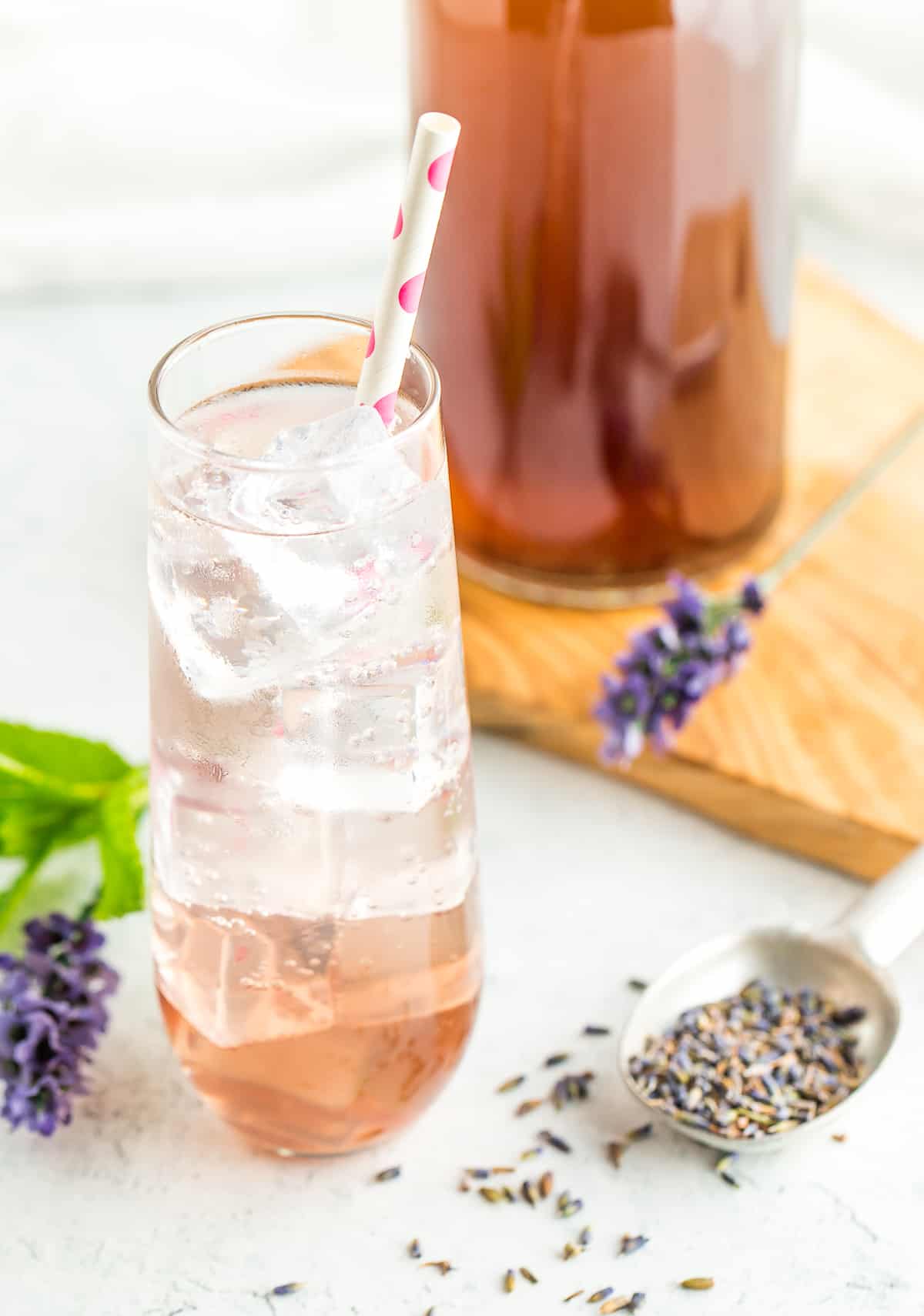 a glass of sparkling water with mint and a bottle of lavender simple syrup.