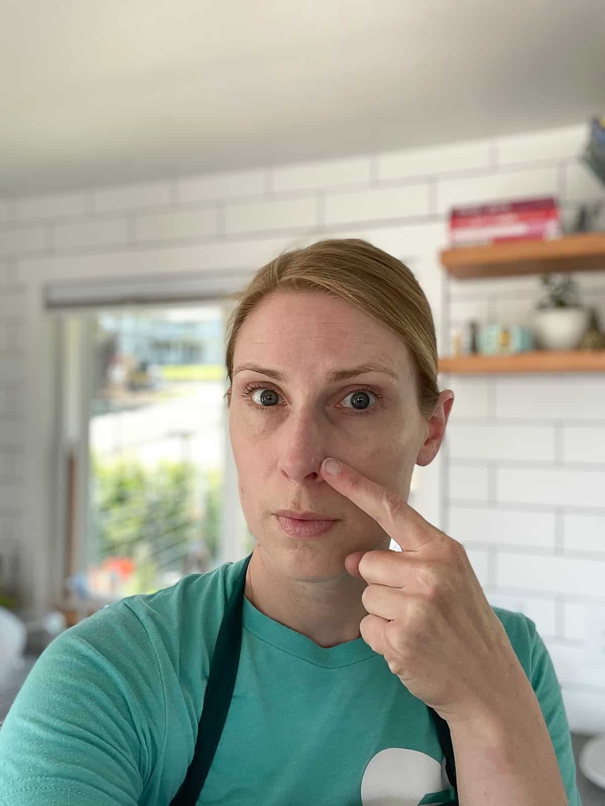 a woman pointing at her nose