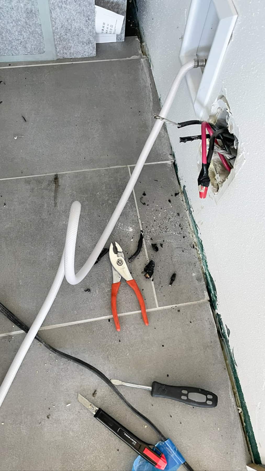tools and singed cords on a grey tile floor.