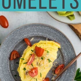 a fluffy air fryer omelet topped with sliced tomatoes, cheese, and parsley on a grey plate.