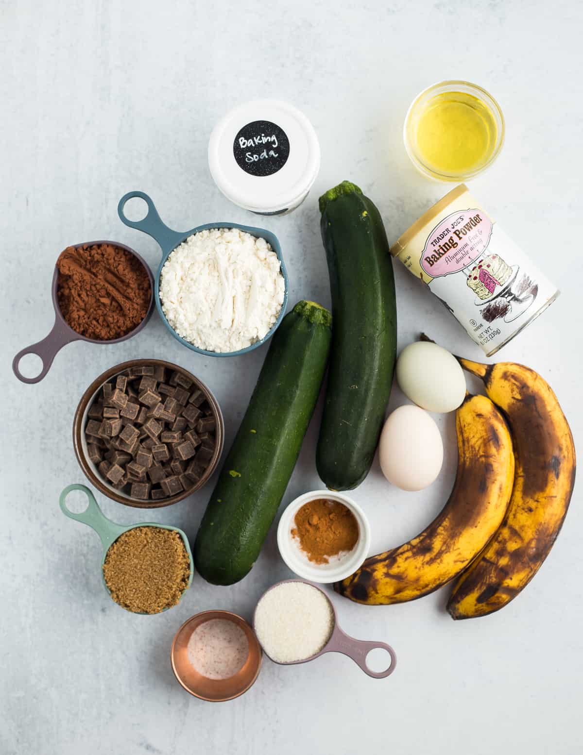 zucchini, bananas, eggs, chocolate chips, and other ingredients on a grey board.