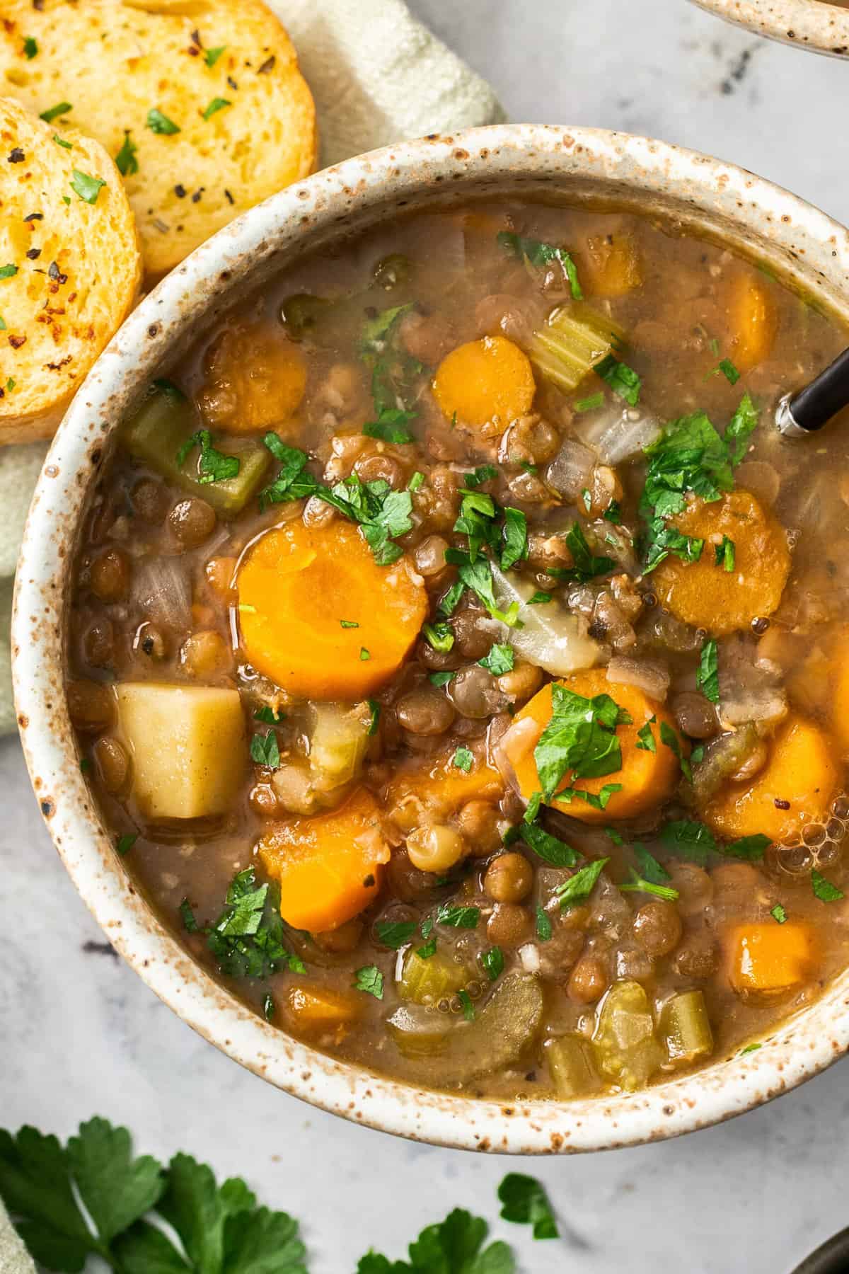 an overhead photo of a bowl of lentil soup topped with fresh parsley.