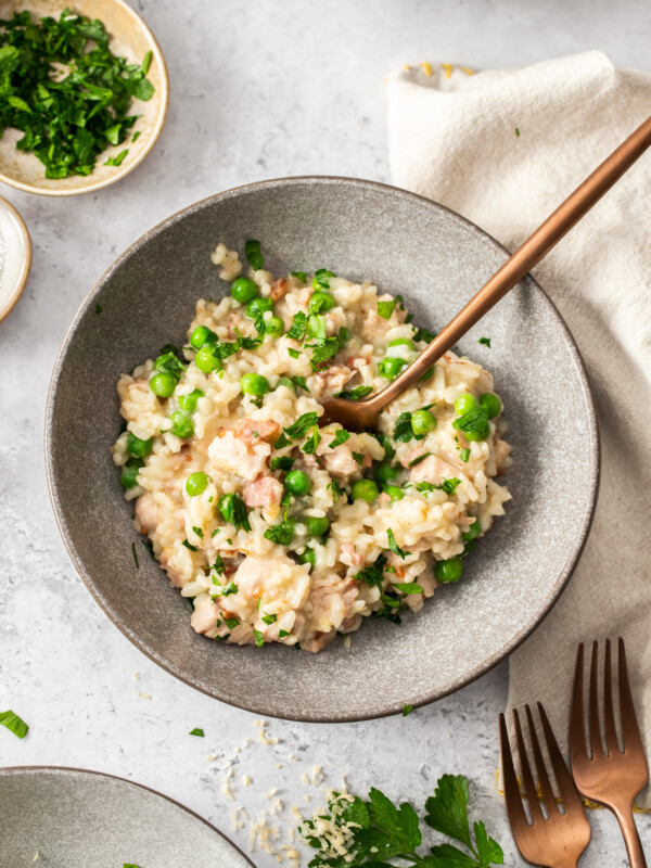 a grey bowl with pea and bacon risotto and rose gold fork.