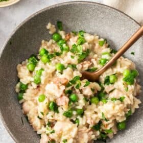 a grey bowl with pea and bacon risotto and rose gold fork.