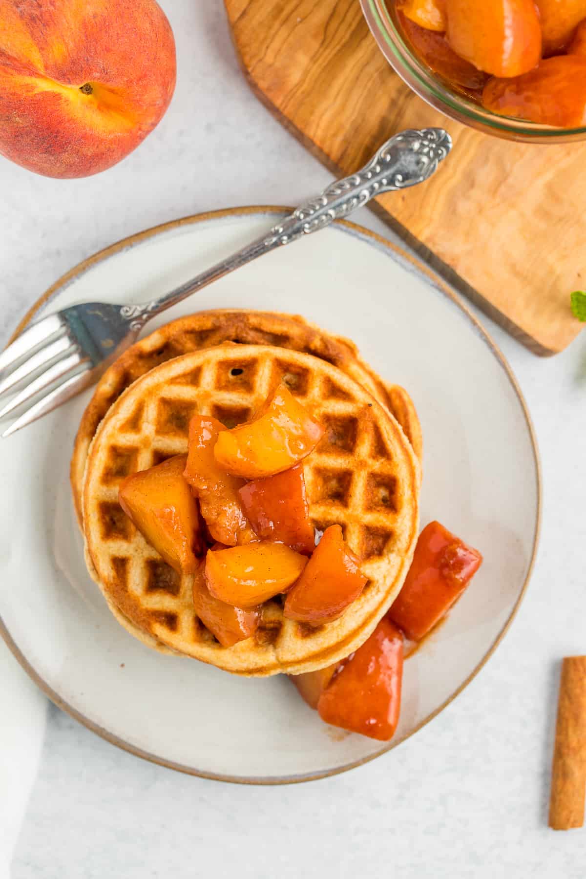 waffles on a plate topped with peach sauce.