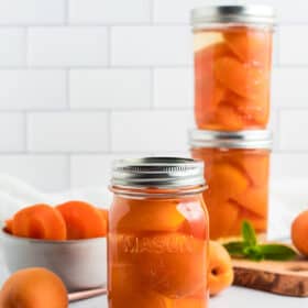 jars of canned apricots against a tile background.