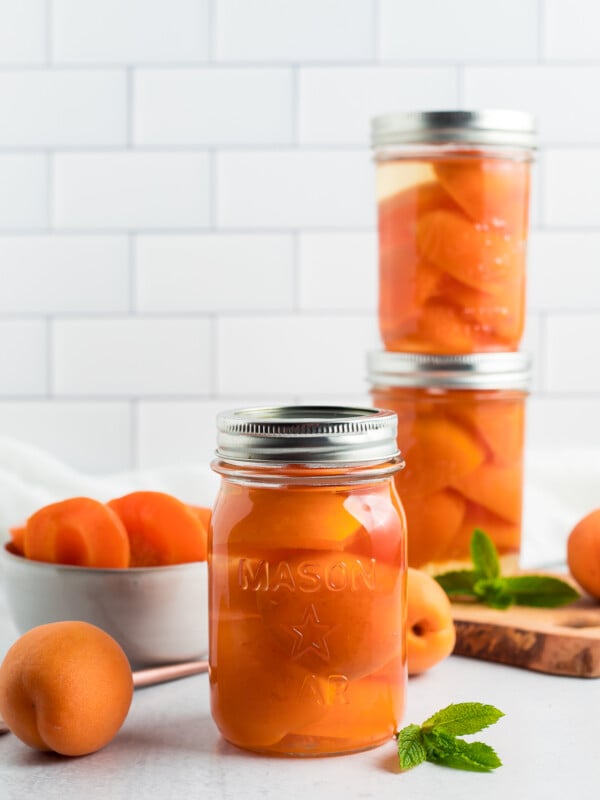 jars of canned apricots against a tile background.