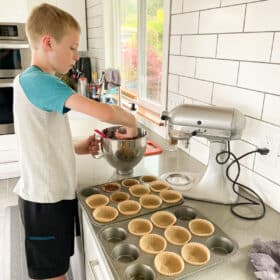 a kid making muffins in a kitchen