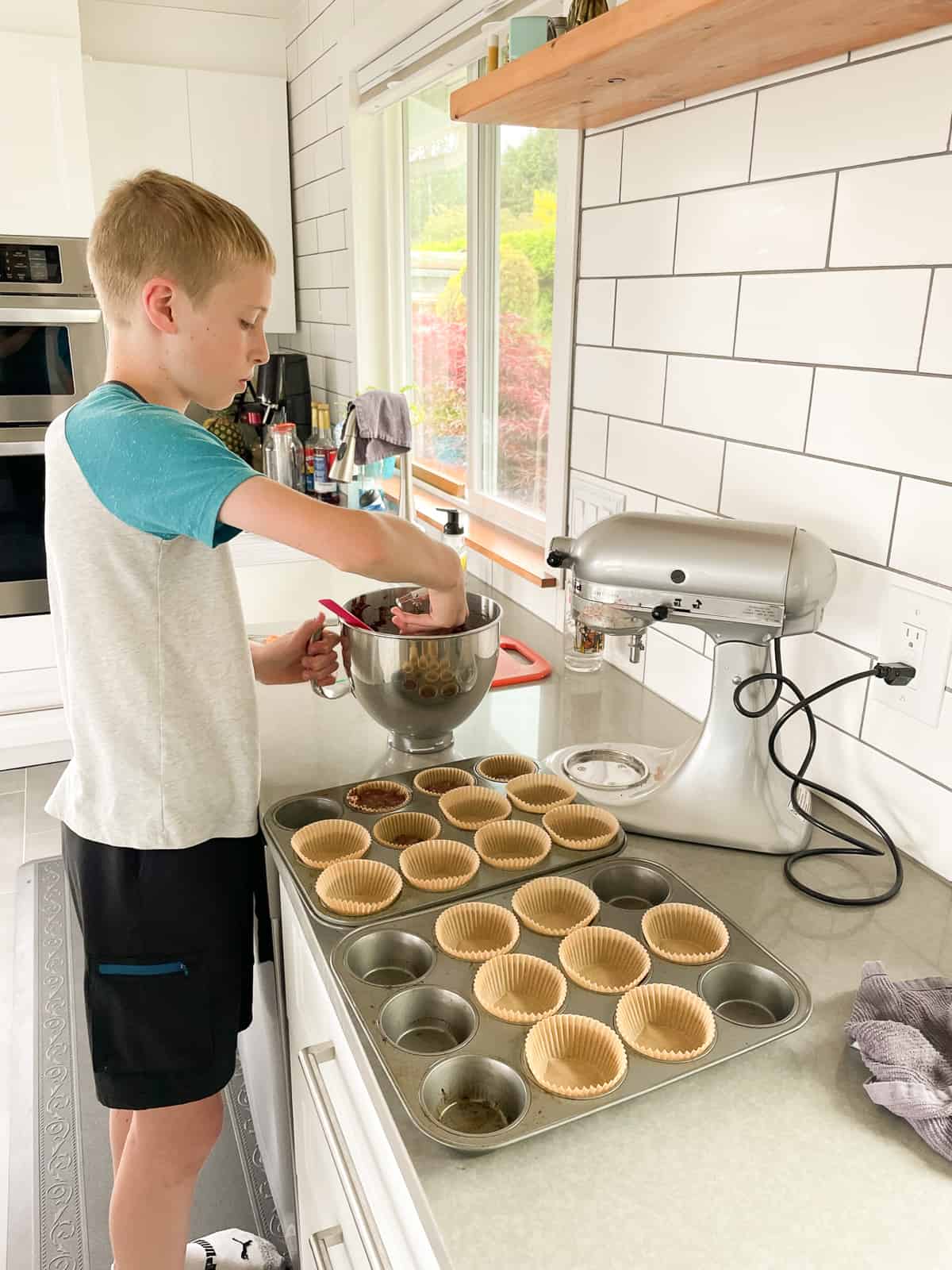 a kid making muffins in a kitchen