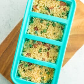 Teal Souper Cubes filled with frozen risotto on a wooden board.