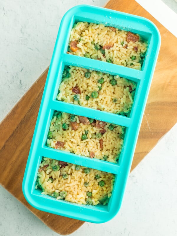 Teal Souper Cubes filled with frozen risotto on a wooden board.