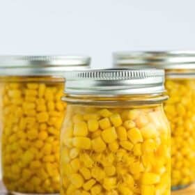 jars of home canned corn on a white board.