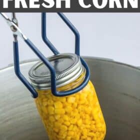 canning tongs lifting a jar of canned sweet corn out of a pressure canner.